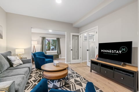 Cozy living room featuring a gray sofa, blue chairs, a wooden coffee table, and a large window with a view.