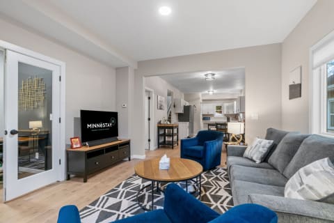 Stylish modern living room featuring a gray sofa, blue chairs, and an entertainment center with a TV.