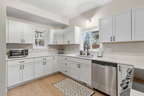 Modern kitchen featuring white cabinetry, a black faucet, and a light wood floor.