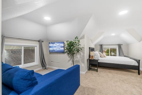 Cozy attic room with blue sofa, bed, and TV.