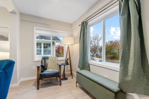 Cozy corner with a chair, small table, and large window showcasing autumn trees.