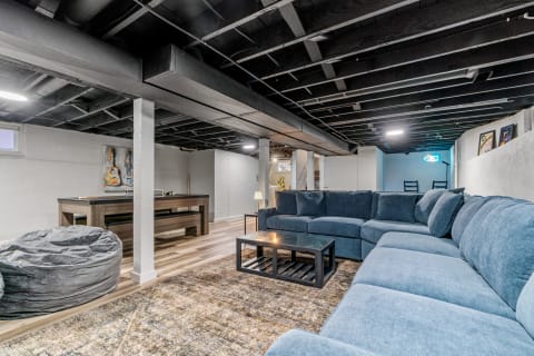 Spacious and inviting basement with sectional sofa, coffee table, and game area.