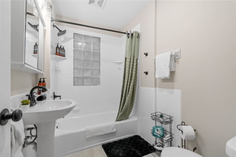 Modern bathroom featuring a shower and bathtub, sink, and neatly arranged toiletries.