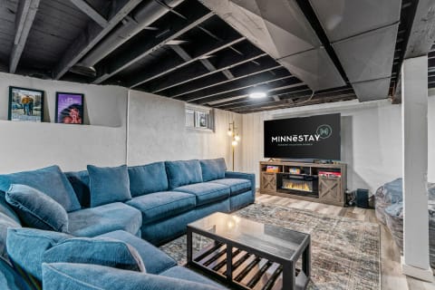 A stylish basement with a blue sectional sofa, television, and unique decor.