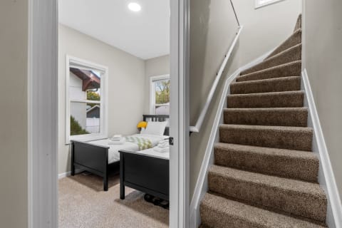 A glimpse into a cozy bedroom featuring twin beds and a staircase.