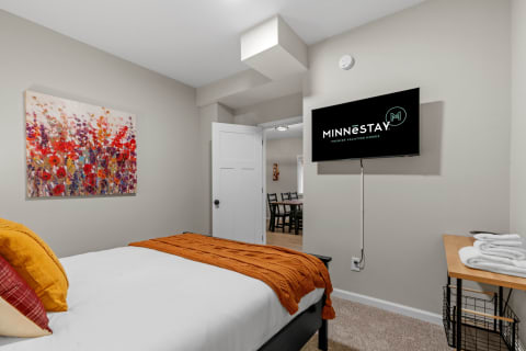 A well-decorated bedroom with colorful artwork and a modern TV.