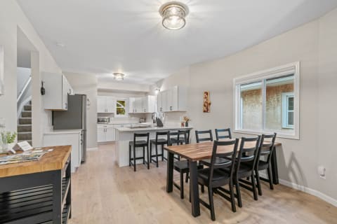 Modern kitchen and dining space featuring wood furniture and white cabinetry.