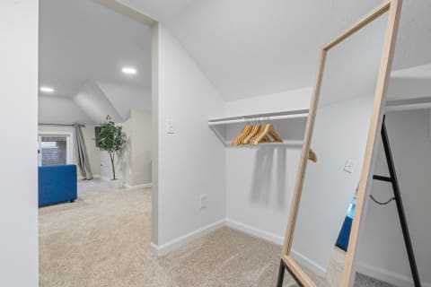 Interior view of an attic space with a full-length mirror and wooden hangers.