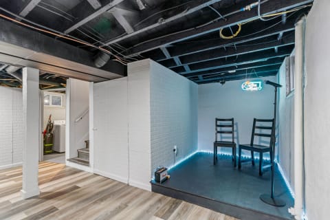 A stylish basement with a small performance area featuring two chairs and a microphone.