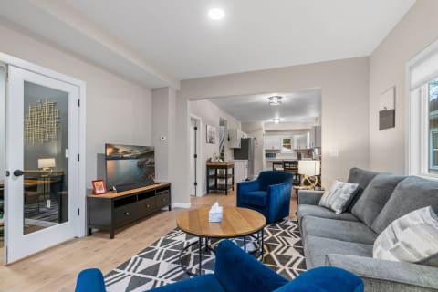 Living room with blue chairs, gray sofa, and a kitchen in the background.