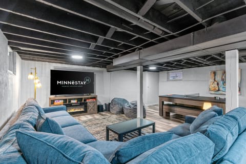 Basement recreation area with a blue sectional sofa and a ping pong table.
