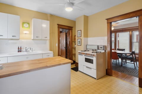Cozy kitchen featuring white cabinets, wood countertop, and a classic gas stove.