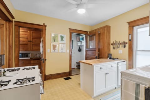 A kitchen with wooden cabinets, a white island, and tree illustrations on the wall.