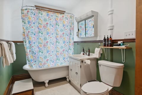 Bathroom with clawfoot tub, floral shower curtain, and modern sink.