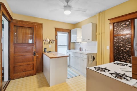 Cozy kitchen with yellow walls, wooden door, white cabinets, and knife rack.