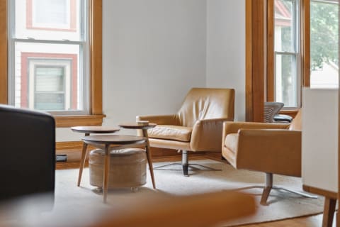 Stylish living room with tan leather chairs and a wooden coffee table near a window.
