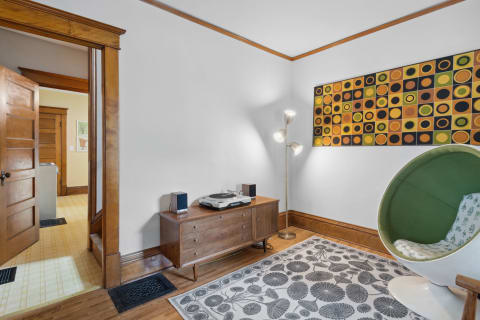 Cozy living room corner featuring a vintage turntable, green pod chair, and colorful wall art.