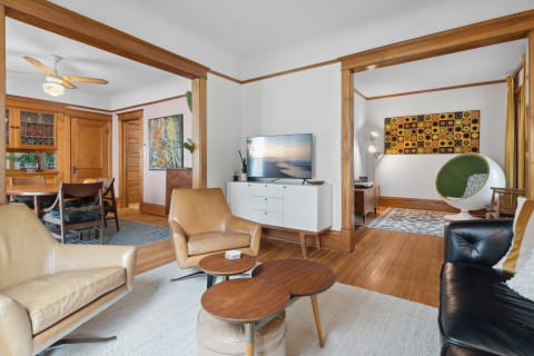 Cozy living room with leather chairs, wooden furniture, and vibrant artwork.