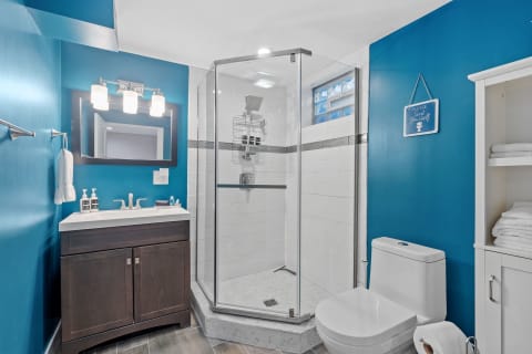 A modern bathroom showcasing vibrant blue walls, a glass shower, and stylish fixtures.