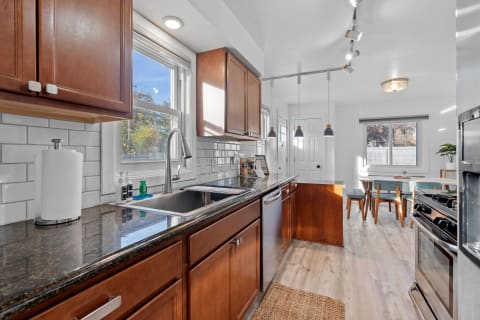 Stylish kitchen with granite countertops, wooden cabinets, and stainless appliances, featuring a dining space.