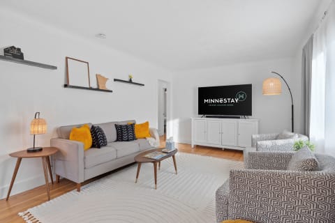 Modern living room featuring a gray sofa, decorative pillows, and a large TV on a white console.