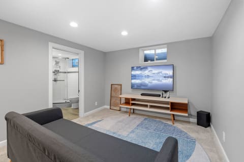 Modern living room featuring a grey couch, wall-mounted TV, and minimalist decor.