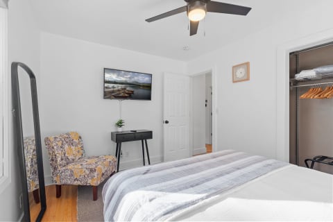Cozy bedroom with a bed, floral chair, and wall-mounted TV