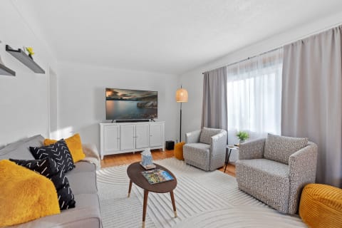 Living room featuring a gray sofa, patterned accent chairs, and a flat-screen TV.