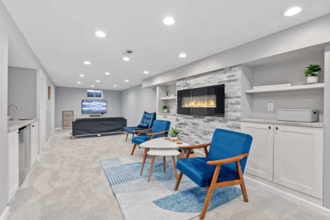 Stylish lower level retreat with blue chairs, a fireplace, and entertainment space.