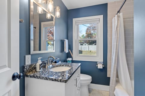 Stylish bathroom featuring granite countertops and deep blue walls with natural light.