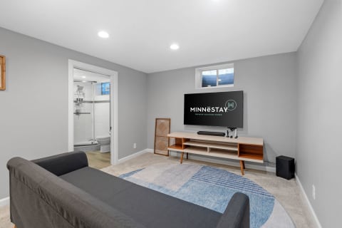 Cozy lower-level living space featuring a couch, a TV, and a private bathroom entrance.
