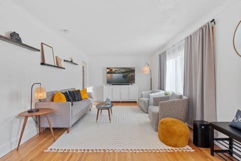 Modern living room with a gray sofa, two patterned chairs, and warm lighting, showcasing a blend of comfort and style.
