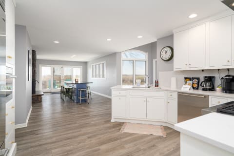 Modern kitchen with white cabinets, wooden flooring, and an inviting dining area.