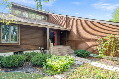 Front view of a modern single-story house with brown siding and a red door.