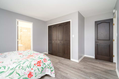 Bright bedroom with floral quilt and dark wood closet.