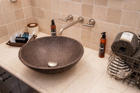 A stylish bathroom sink with a dark stone basin, modern faucets, and neatly arranged toiletries.