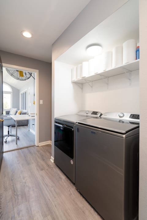 Interior view of a contemporary laundry room with gray walls and stainless steel appliances.