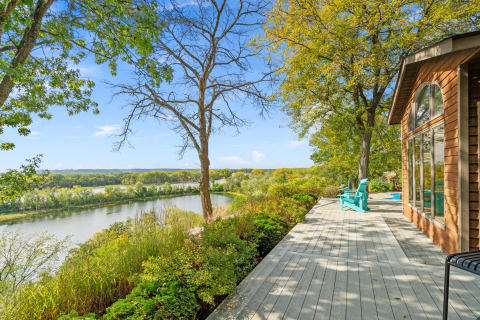 A wooden deck overlooking a calm river surrounded by autumn foliage.