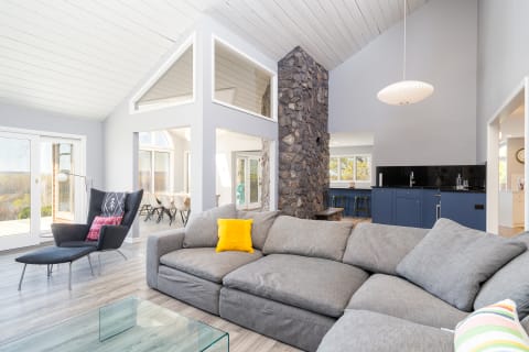 A contemporary living room featuring a gray sectional sofa, black lounge chair, and a stone fireplace.