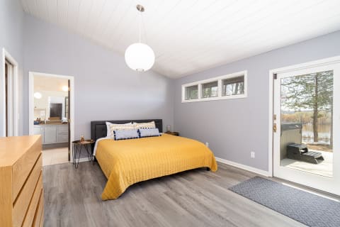 Modern bedroom with gray walls, yellow bedspread, and views of nature.