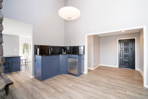 A modern kitchen featuring navy cabinets, black granite countertops, and a bright pendant light.