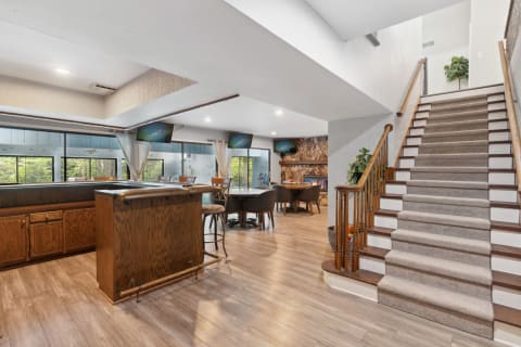 Interior view of a modern living space with bar, dining area, and staircase.
