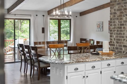 Cozy dining room featuring a wooden table and chairs, a chandelier, and a view of the outdoors through sliding glass doors.
