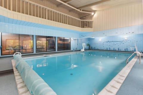Indoor swimming pool featuring blue walls and large windows showcasing a view of the outdoors.