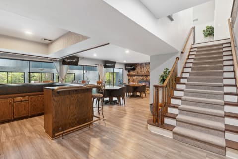 Interior view of a spacious living area featuring a bar, seating, and staircase.