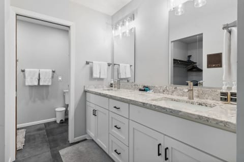 Modern bathroom with a wide vanity, gray countertop, and glass light fixtures.