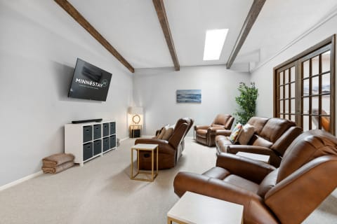 Cozy living room with leather reclining chairs, a media console, and natural light from a skylight.