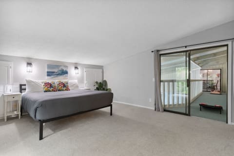 A well-decorated bedroom with gray bedspread, floral pillows, and a view of a balcony.