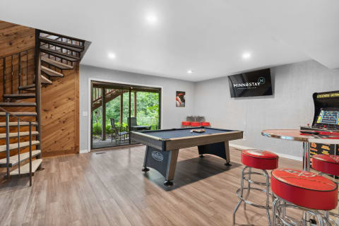 Indoor recreational room featuring a pool table, bar seating, and a view of the outdoors.