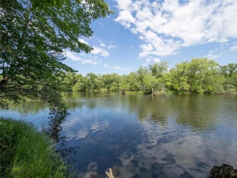 Serene view of a river with green trees and bright sky.